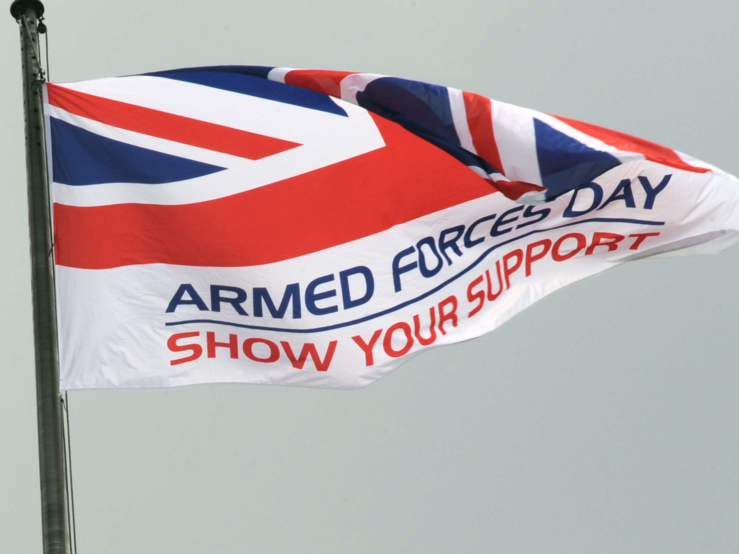 Flag flying atop of a flag pole with text Armed Forces Day Show Your Support on it.